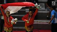 Pasangan pesilat Indonesia peraih medali emas, Ayu Sidan Wilantari dan Ni Made Dwiyanti membentangkan bendera merah putih usai penyerahan medali nomor seni ganda putri di Padepokan Pencak Silat TMII, Jakarta, Rabu (29/8). (Merdeka.com/Imam Buhori)