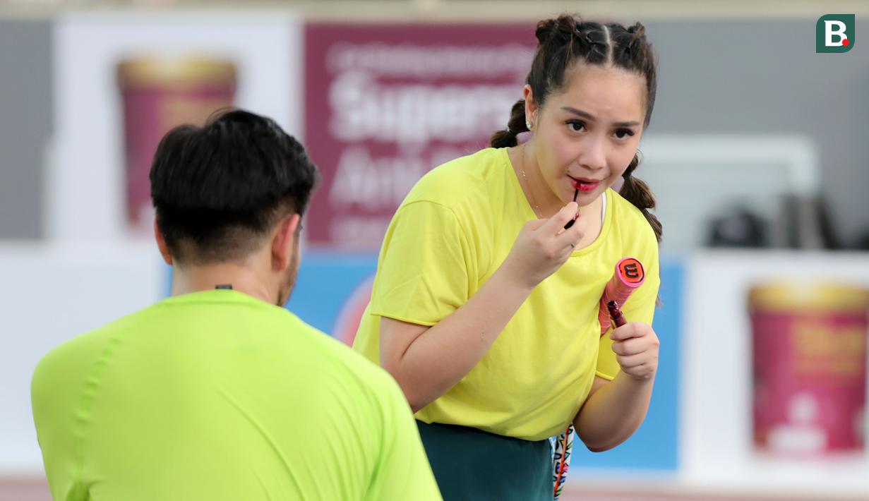 Selebritas Nagita Slavina memakai lipstik pada laga tenis nomor ganda campuran Turnamen Olahraga Selebriti Indonesia (TOSI) yang digelar di GOR UNJ, Jakarta, Sabtu (15/07/2023). Gigi, sapaan Nagita Slavina, yang berpasangan dengan Ritchie Ismail atau dikenal sebagai Jeje Govinda kalah dari pasangan Gege dan Ibnu Jamil dua set langsung  (5-7, 6(2)-7(7)). (Bola.com/Abdul Aziz)