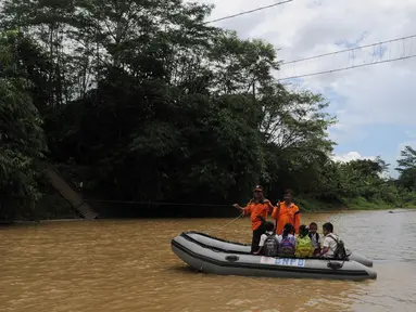 Sejumlah siswa menyeberangi sungai Ciberang mengunakan perahu karet milik BNPB di Lebak, Banten, Senin (16/3). Pasca robohnya jembatan gantung di atas Sungai Ciberang, warga terpaksa menyeberang mengunakan perahu karet. (Liputan6.com/Herman Zakharia)