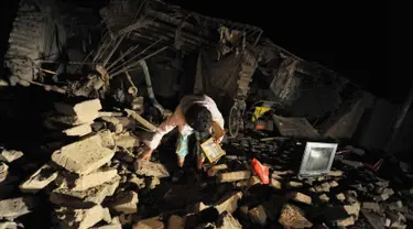 Seorang wanita mengambil barang miliknya di rumahnya yang hancur setelah gempa di Bella Union, Peru, (14/1). Gempa 7,1 skala Richter mengguncang Peru pada Minggu, 14 Januari 2018. (AP Photo / Charlie Reyna)