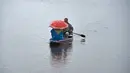 Seorang awak perahu Kashmir mengangkut penumpang saat hujan di Danau Dal di Srinagar (20/3). Di Sepanjang tepi Danau Dal terdapat Ghate yang merupakan tempat bersandarnya Shikara. (AFP Photo/Tauseef Mustafa)