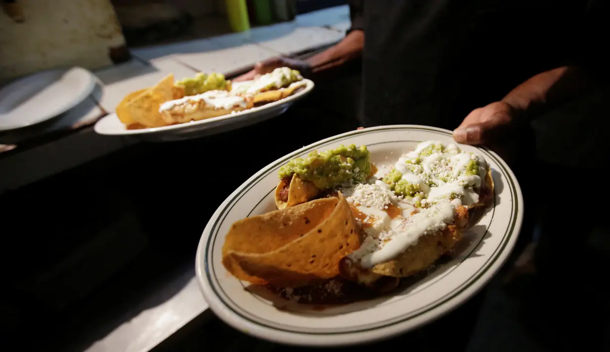 Seorang koki dari restoran El Tizoncito membawa piring berisi makanan di Caracas, 13 September 2016. Karena krisis ekonomi di Venezuela, sebuah restoran menawarkan seporsi makanan yang bisa ditukar dengan 2 liter minyak goreng. (REUTERS/Henry Romero)