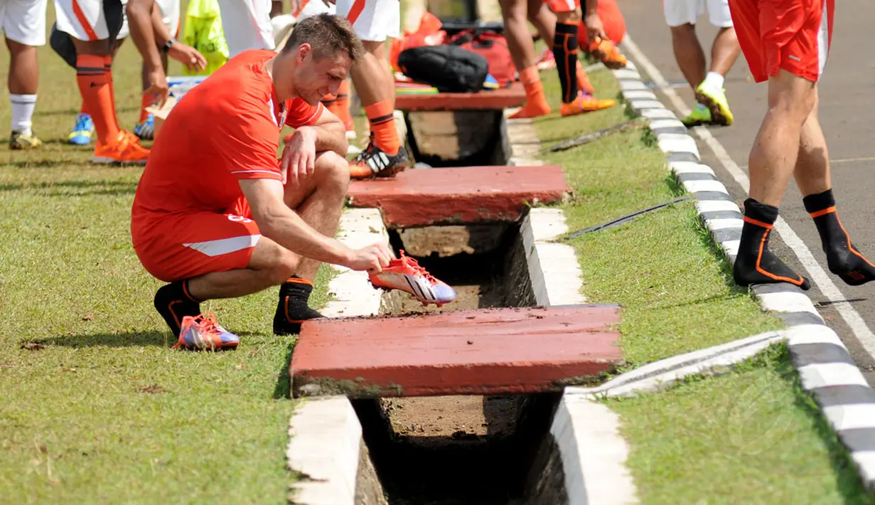 Pemain asing Persija Jakarta, Yevgeni Kabayev membersihkan sepatunya usai berlatih bersama di lapangan Yon Zikon 13/KE, Jakarta, (23/22/2014). (Liputan6.com/Helmi Fithriansyah)