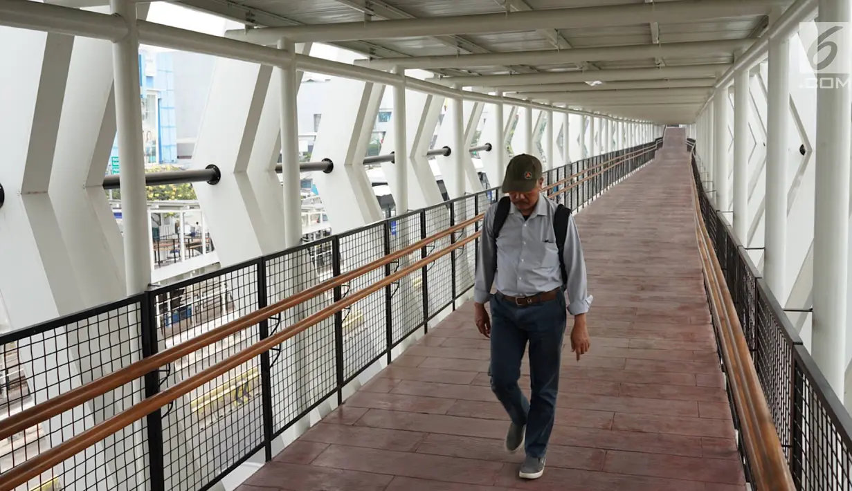 Warga melintasi jembatan penyeberangan (Skybridge) yang menghubungkan Stasiun LRT Velodrome dengan Halte Transjakarta Pemuda di Rawamangun, Jakarta, Senin (29/7/2019). Skybridge ini bertujuan memudahkan integrasi penumpang LRT menuju Transjakarta atau sebaliknya. (Liputan6.com/Immanuel Antonius)