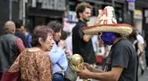 Seorang pedagang kaki lima yang mengenakan topeng gulat tradisional Meksiko menunjukkan suvenir berbentuk piala Piala Dunia kepada pejalan kaki di Mexico City, Senin 8 Juni 2026. (Yuri CORTEZ/AFP)