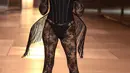Carla Bruni tampil stunning dengan bustier dan lace pants serba hitam. Ia menyempurnakan penampilannya dengan sayap fringe yang unik. [@runway.dolls]