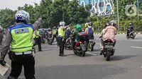 Petugas kepolisian lalu lintas memberhentikan pengendara motor saat Operasi Zebra Jaya 2020 di kawasan Cawang, Jakarta, Senin (26/10/2020). Operasi Zebra Jaya dilaksanakan pada 26 Oktober-8 November 2020 untuk menekan jumlah pelanggaran lalu lintas. (Liputan6.com/Faizal Fanani)