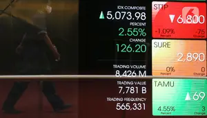 Pekerja melintas di depan layar yang menampilkan informasi pergerakan saham di gedung Bursa Efek Indonesia, Jakarta, Senin (8/6/2020).  Indeks Harga Saham Gabungan (IHSG) menguat 1,34% ke level 5.014,08 pada pembukaan perdagangan sesi I, Senin (8/6). (Liputan6.com/Angga Yuniar)