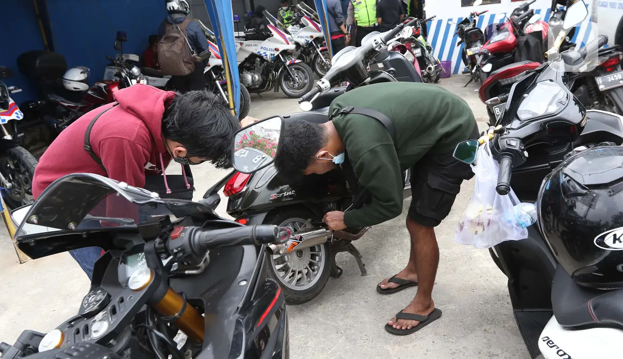 Pengendara motor mencopot knalpot bising usai terjaring razia yang digelar Satlantas Polres Metro Depok di Jalan Margonda Raya, Depok, Kamis (18/3/2021). Puluhan motor berknalpot bising yang terjaring razia diwajibkan mengganti knalpot dan diberi sanksi tilang. (Liputan6.com/Helmi Fithriansyah)