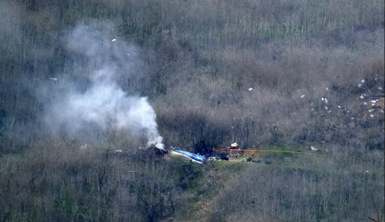 Asap mengepul dari helikopter yang ditumpangi pebasket NBA Kobe Bryant di sisi bukit di Calabasas, California (26/1/2020). Kecelakaan helikopter di Calabasas, California, menewaskan legenda NBA Kobe Bryant, Minggu 26 Januari waktu setempat. (AP Photo/Richard Vogel)