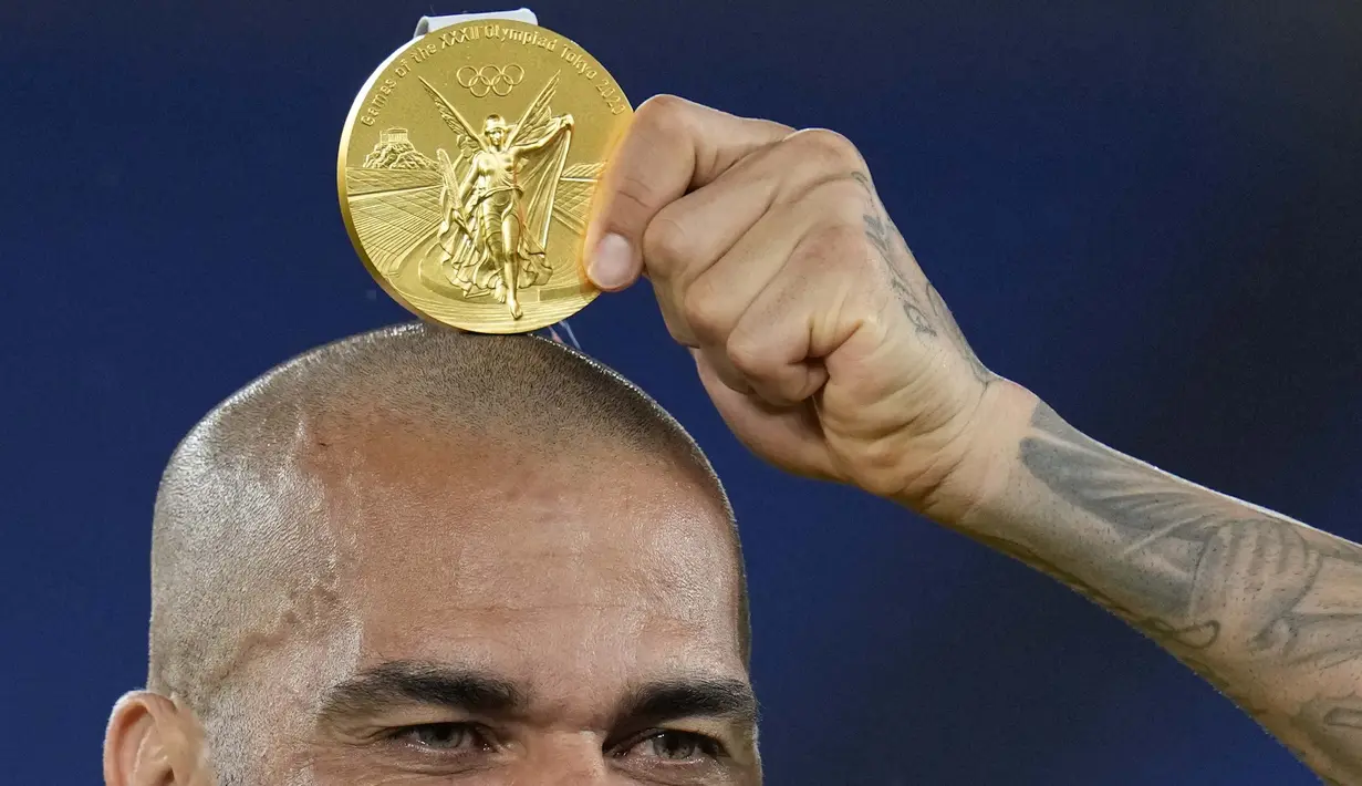 Kapten Timnas Brasil, Dani Alves berpose dengan medali emas yang diperoleh Brasil usai mengalahkan Spanyol dalam pertandingan final sepak bola putra pada Olimpiade Tokyo 2020, Sabtu (7/8/2021). (Foto: AP/Fernando Vergara)