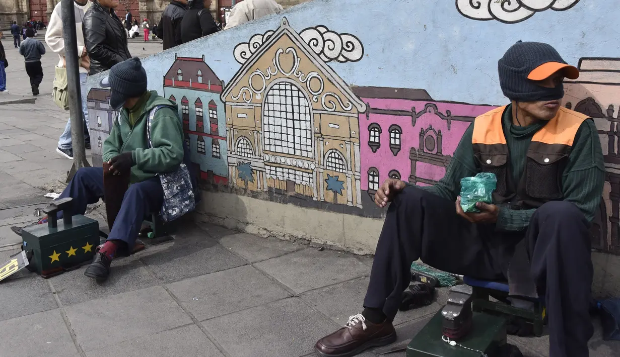 Dua tukang semir sepatu menunggu pelanggan di kawasan La Paz, Bolivia (29/11). Banyak diantara mereka masih menjalani pendidikan di sekolah dan universitas. (AFP PHOTO/Aizar Raldes)