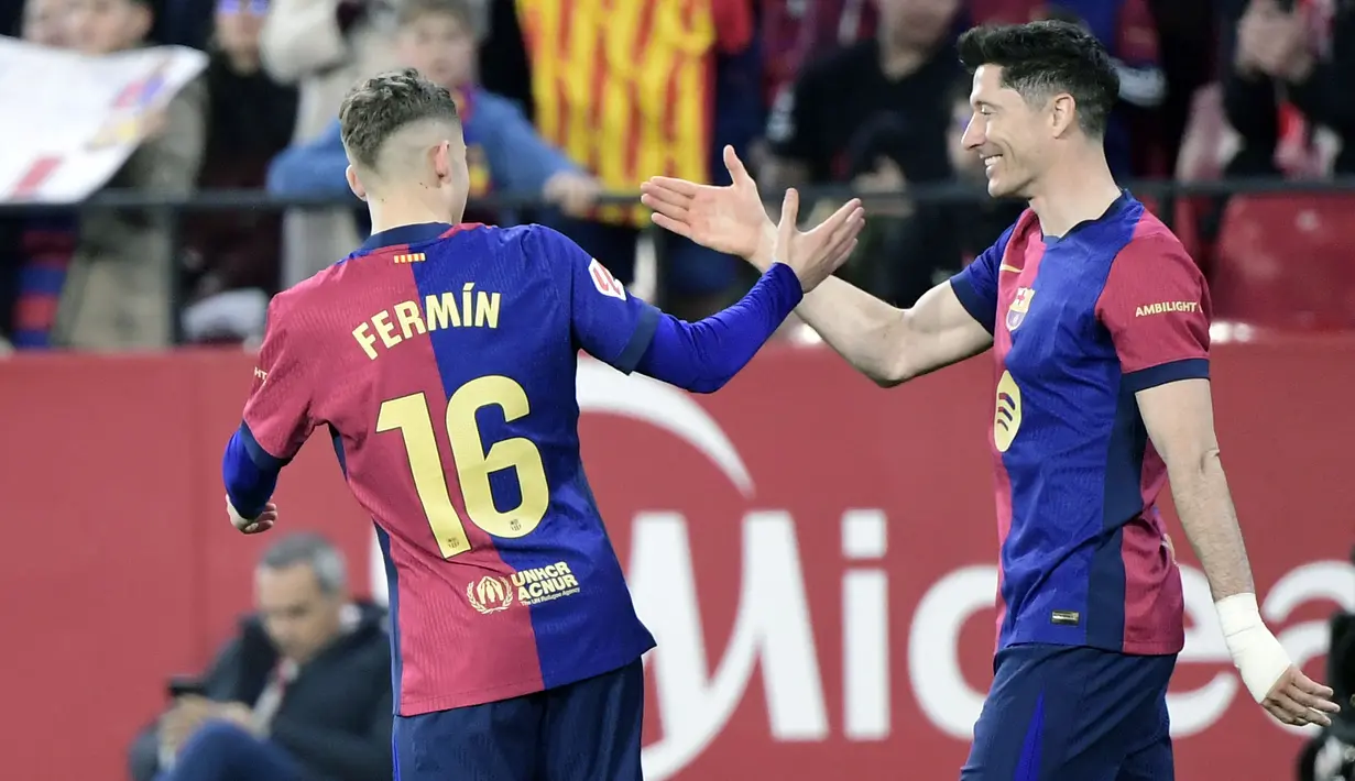 Pemain Barcelona, Fermin Lopez merayakan gol bersama Robert Lewandowski dalam laga lanjutan Liga Spanyol 2024/2025 melawan Sevilla di Ramon Sanchez Pizjuan Stadium, Sevilla, Spanyol, Senin (10/02/2025) dini hari WIB. (AFP/Cristina Quicler)