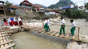 Siswa melintasi jembatan darurat berbahan bambu di Kampung Ciasahan, Desa Sukamaju, Kabupaten Bogor, Kamis (6/2/2020). Pembangunan kembali jembatan Ciasahan yang ambruk akibat banjir bandang pada Rabu (1/1) itu diharapkan mampu memulihkan aktivitas dan perekonomian warga. (merdeka.com/Arie Basuki)