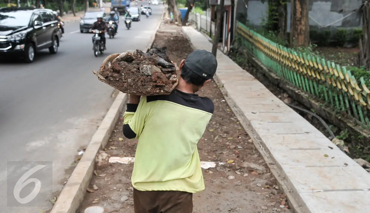 Pekerja memanggul tanah ketika menyelesaikan pembangunan trotoar di Jalan Raya Ragunan, Jakarta, Rabu (12/10). Sudin Bina Marga Jaksel menganggarkan Rp79 miliar untuk pembangunan dan perbaikan trotoar di 10 kecamatan Jaksel. (Liputan6.com/Yoppy Renato)