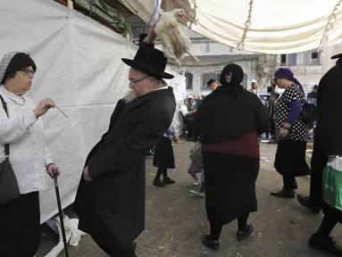 Seorang pria Yahudi Ultra-Ortodoks mengangkat ayam saat melakukan ritual Kaparot di Yerusalem (27/9). Dalam ritual ini ayam putih disembelih sebagai syarat simbolis dari penebusan dosa. (AFP Photo/Manahem Kahana)