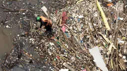 Petugas kebersihan Pemprov DKI Jakarta mencoba mengurai sampah yang terbawa arus di Pintu air Manggarai, Jakarta, Senin (2/10). Pembersihan itu dilakukan untuk melancarkan aliran Sungai Ciliwung yang melewati Pintu Air Manggarai (Liputan6.com/Johan Tallo)