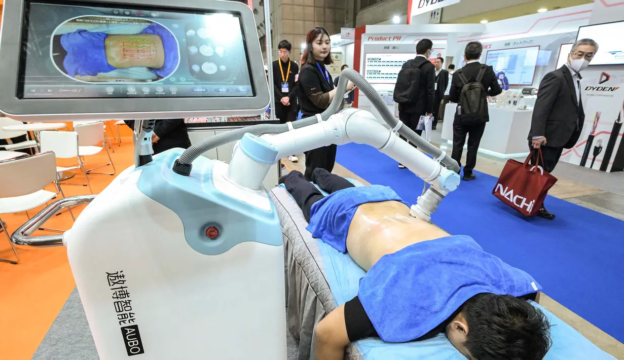 Robot memijat punggung seorang pria di stan AUBO Robotics. (Richard A. Brooks/AFP)
