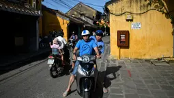 Gambar pada 14 September 2019 menunjukkan pria Vietnam menaiki skuter di kota tua Hoi An. Kota Tua Hoi An merupakan destinasi wisata yang cukup populer di Vietnam, didukung oleh statusnya sebagai salah satu Unesco World Heritage Site. (Manan VATSYAYANA/AFP)