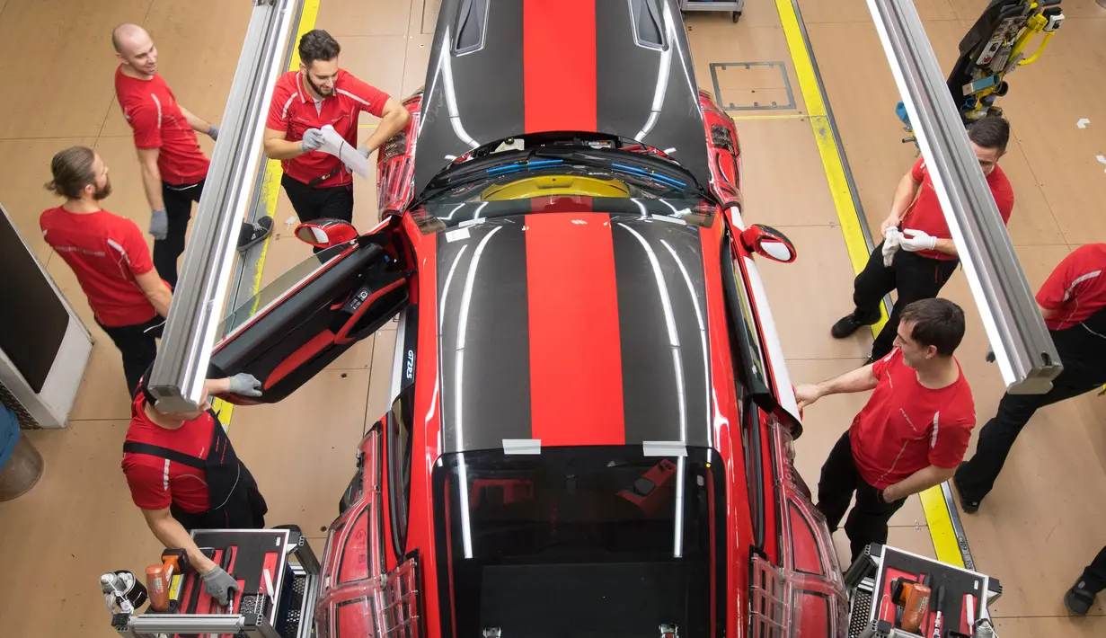 Pekerja memasang pintu mobil sport Porsche GT2RS di pabrik Porsche di Stuttgart, Jerman (26/1). Perusahaan Porsche membagikan bonus besar kepada karyawannya karena hasil penjualan mereka mencapai rekor tertinggi tahun lalu. (AFP Photo/Thomas Kienzle)
