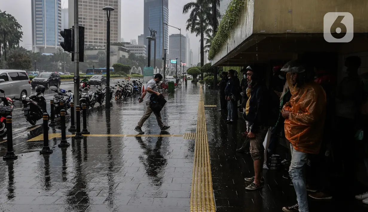 Aktivitas warga saat hujan mengguyur kawasan Jakarta, Selasa (16/2/2021). Sebagai tahap awal vaksinasi COVID-19 tahap kedua bagi pekerja publik akan dimulai dari para pedagang Pasar Tanah Abang pada Rabu 17 Februari 2021. (Liputan6.com/Johan Tallo)