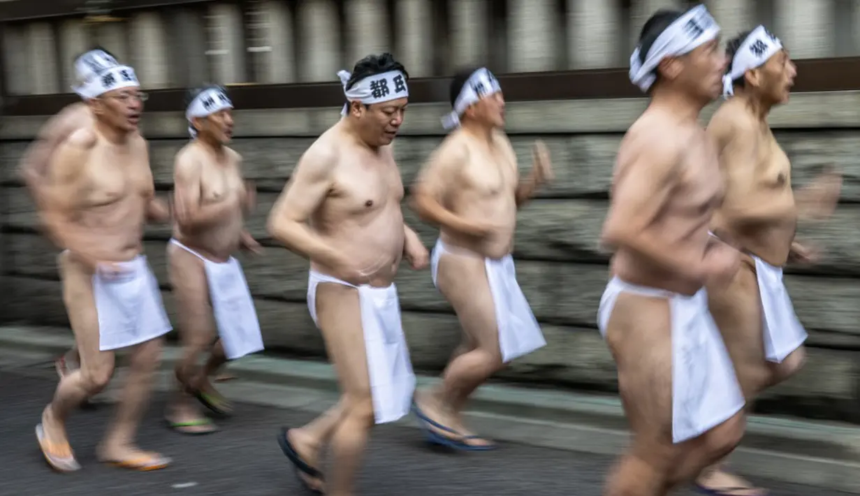 Penganut Shinto berlari saat melakukan pemanasan sebelum mandi dengan air dingin di Kuil Teppozu Inari, Tokyo, Jepang, 8 Januari 2023. Ritual Tahun Baru ini dilakukan untuk memurnikan jiwa dan raga. (Philip FONG/AFP)