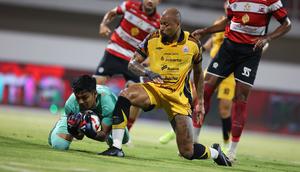 Pemain Persija Jakarta, Gustavo Almeida (kanan) berduel dengan kiper Madura United pada lanjutan BRI Super League 2025/2026 di Stadion Gelora Ratu Pamelingan, Jumat (24/10/2025) malam WIB. (Bola.com/Abdul Aziz).