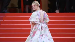Elle Fanning menaiki tangga karpet merah saat tiba menghadiri screening film "Les Miserables" dalam acara Festival Film Cannes ke-72 di Prancis (15/5/2019). Aktris 21 tahun ini tampil cantik mengenakan gaun taman haute couture karya Valentino. (AP Photo/Arthur Mola)