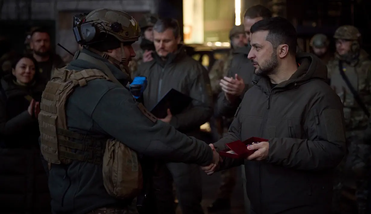 Presiden Ukraina Volodymyr Zelenskyy (kanan) memberikan penghargaan kepada seorang tentara di lokasi pertempuran terberat melawan Rusia di Bakhmut, Ukraina, 20 Desember 2022. Volodymyr Zelenskyy melakukan kunjungan mendadak ke Bakhmut. (Ukrainian Presidential Press Office via AP)