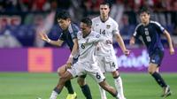 Pemain timnas Indonesia Beckham Putra Nugraha (tengah) berebut bola dengan gelandang Jepang Wataru Endo (kiri) saat pertandingan putaran ketiga Kualifikasi Piala Dunia 2026 zona Asia grup C antara Jepang dan Indonesia di Osaka pada 10 Juni 2025. (PAUL MILLER/AFP)