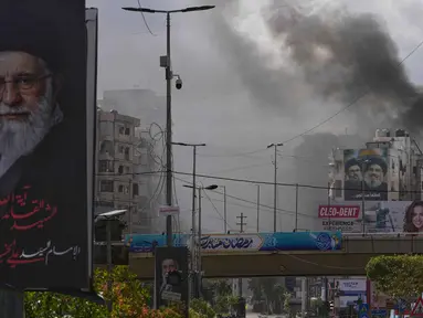 Kepulan asap terlihat di balik potret mendiang Pemimpin Tertinggi Iran, Ayatollah Ali Khamenei, setelah serangan udara Israel di Dahiyeh, pinggiran selatan Beirut, Lebanon, Senin, 30 Maret 2026. Serangan udara Israel kembali menghantam wilayah Dahiyeh, pinggiran selatan Beirut, Lebanon. (AP Photo/Hassan Ammar)