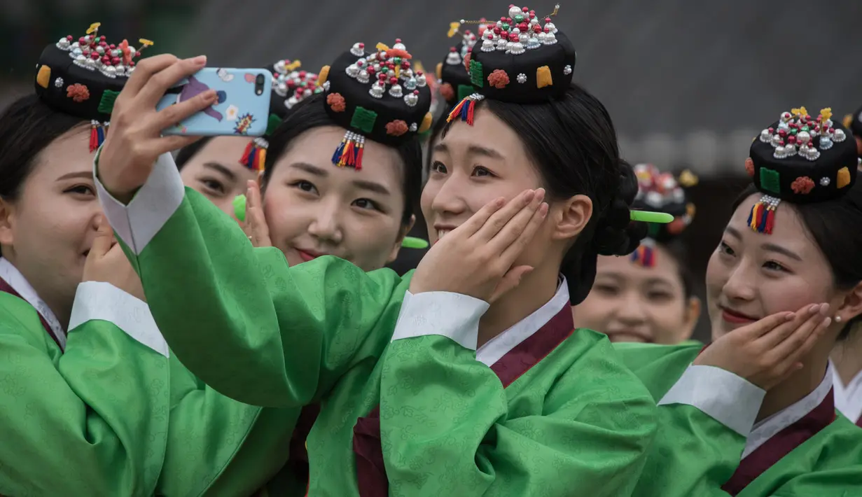 Pelajar berswafoto sambil mengenakan kostum tradisional Korea Selatan (Korsel) setelah upacara Coming of Age Day di Namsan Hanok Village, Seoul, Senin (15/5). Coming of age day atau Hari Kedewasaan dirayakan pada minggu ketiga bulan Mei. (Ed JONES/AFP)