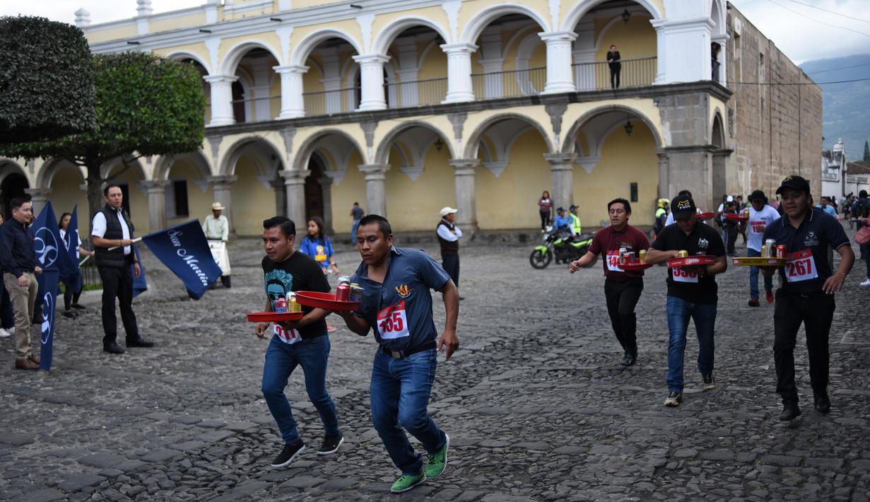 Pramusaji dari berbagai restoran berpartisipasi dalam Waiters Race ke-16 di Antigua, barat daya Ibu Kota Guatemala City, Rabu (14/11). Peserta diminta unjuk kebolehan menggunakan satu tangan membawa nampan berisi minuman. (JOHAN ORDONEZ/AFP)