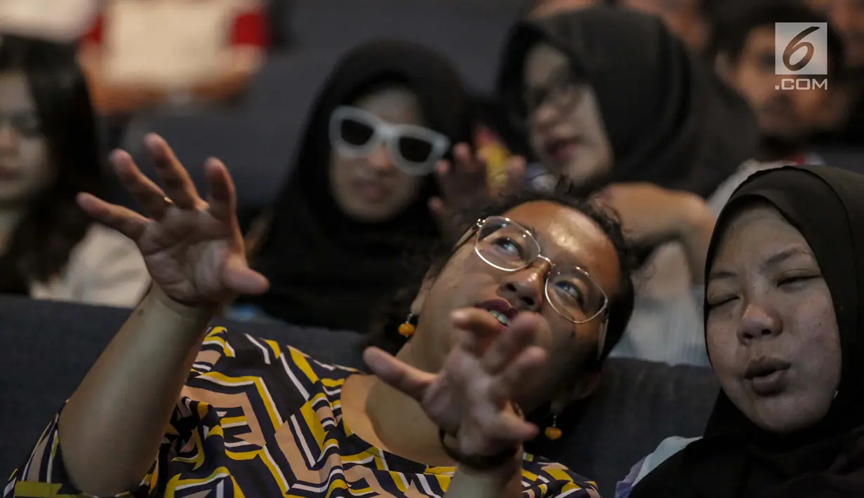 Relawan bisik menjelaskan alur cerita kepada tunanetra saat menyaksikan Bioskop Bisik di Pavilliun 28, Jakarta, Minggu (14/1). Hal ini membuat penyandang tunanetra dapat mengerti dan merasakan emosi yang ada di film tersebut. (Liputan6.com/Faizal Fanani)