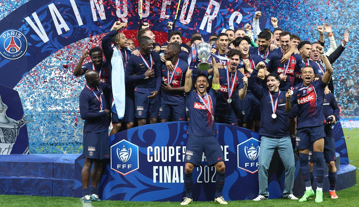 Bek Paris Saint-Germain #05 Marquinhos (tengah) mengangkat trofi Coupe de France 2023/2024 saat berselebrasi dengan timnya setelah menang atas Olympique Lyon pada laga final di Stadion Pierre-Mauroy, Minggu (26/5/2024) dini hari WIB. (FRANCK FIFE / AFP)