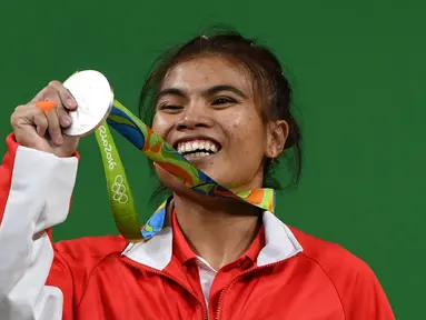 Indonesia meraih medali pertama pada Olimpiade Rio de Janeiro 2016 dari cabang angkat besi, Sabtu (6/8/2016) waktu Brasil atau Minggu (7/8/2016) WIB. Lifter Sri Wahyuni Agustiani (kiri) merebut perak kelas 48 kg putri. (AFP/Goh Chai Hin)