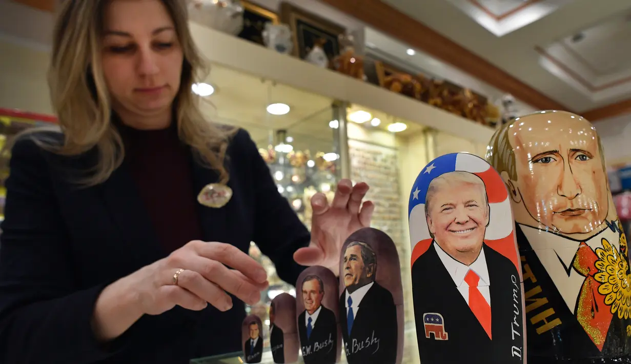 Penjaga toko manampilkan Matryoshka yang berkarakter Putin dan Trumph di Moskow, Rusia (16/1). Matryoshka adalah boneka kayu bertumpuk yang berasal dari Rusia. (AFP/Alexander Nemenov)