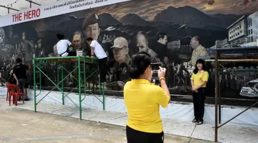 Pengunjung berfoto depan mural raksasa berjudul 'The Heroes' di Chiang Rai, Thailand, 18 Juli 2018. Mural itu untuk menghormati upaya penyelamatan 12 remaja dan pelatih sepak bola yang terperangkap di  gua lebih dari dua minggu. (AFP/Lillian SUWANRUMPHA)