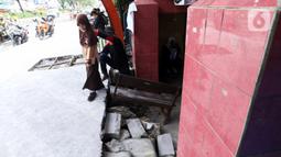 Seorang siswa berjalan keluar melintasi jalan darurat yang dibuat pihak sekolah di SDN Pondok Cina 1, Depok, Jawa Barat, Rabu (9/11/2022). Pembangunan trotoar Jalan Margonda Raya yang tidak membuat jalan darurat untuk siswa tersebut menghalangi pintu masuk SDN Pondok Cina 1 serta membahayakan siswa. (Liputan6.com/Herman Zakharia)
