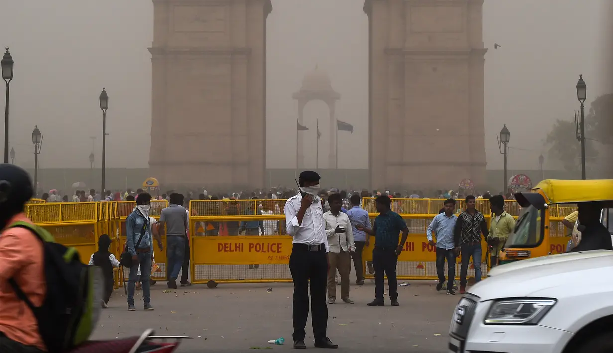 Seorang polisi lalu lintas menutupi wajahnya saat badai debu menyelimuti New Delhi, India, Rabu (2/5). Selain menewaskan 77 orang, sebanyak 143 lainnya juga terluka. (CHANDAN KHANNA/AFP)