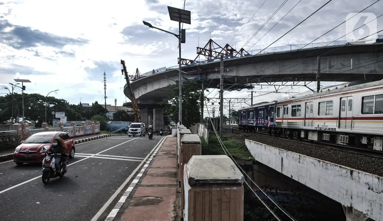 Kendaraan dan kereta Commuter Line saat melintas di bawah proyek jalur lintas atas (flyover) Cakung, Jakarta, Kamis (17/12/2020). Flyover dengan biaya pembangunan mencapai Rp 261 miliar ini diharapkan mampu mengatasi kemacetan yang kerap terjadi di kawasan tersebut. (merdeka.com/Iqbal Nugroho)