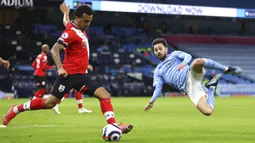 Pemain Southampton Ryan Bertrand (kiri) menendang bola di depan pemain Manchester City Bernardo Silva pada pertandingan Liga Inggris di Etihad Stadium, Manchester, Inggris, Rabu (10/3/2021). Manchester City menang 5-2. (Clive Brunskill/Pool via AP)