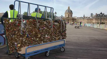 Para pekerja memindahkan sebuah pagar besi yang dipenuhi gembok cinta di Jembatan Pont des Arts di atas Sungai Seine, Paris, Perancis, Senin (1/6/2015). (REUTERS/Philippe Wojazer)