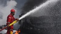 Seorang pekerja dari tim Fire Fighter menyemprotkan busa (foam) untuk memadamkan api pada insiden tangki Pertamina di Kilang Balongan RU VI, Indramayu, Rabu (31/3). Pertamina RU VI dan Unit RU yang ada di Indonesia bersama Damkar Cirebon berupaya memadamkan. (Dok. Humas Pertamina)