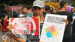 Seorang pria dari front Perjuangan Rakyat menunjukan poster saat melakukan aksi di Jakarta, Minggu (5/2). Aksi tersebut untuk menolak kebijakan Trump atas keputusannya melarang masuknya warga muslim di 7 negara selama 90 hari. (Liputan6.com/Angga Yuniar)