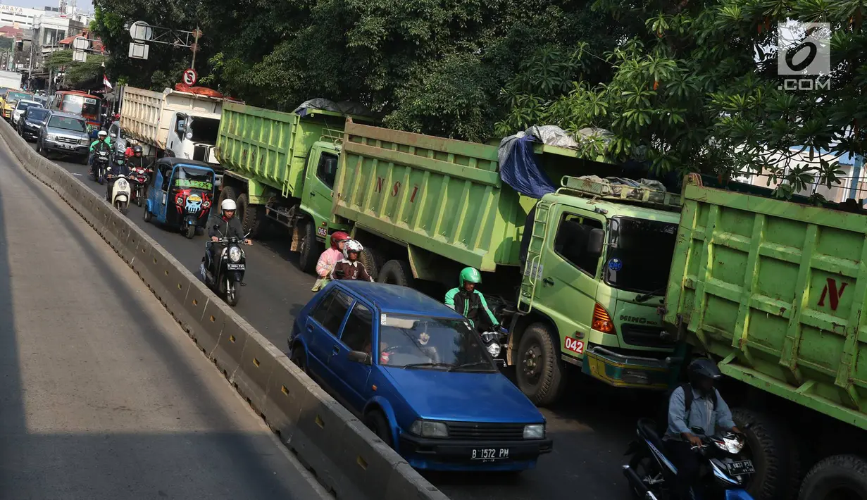 Pengendara mengantre melintas disebelah deretan truk proyek pembangunan Pasar Rumput yang parkir di tepi Jalan Sultan Agung, Jakarta, Selasa (8/8). (Liputan6.com/Immanuel Antonius)