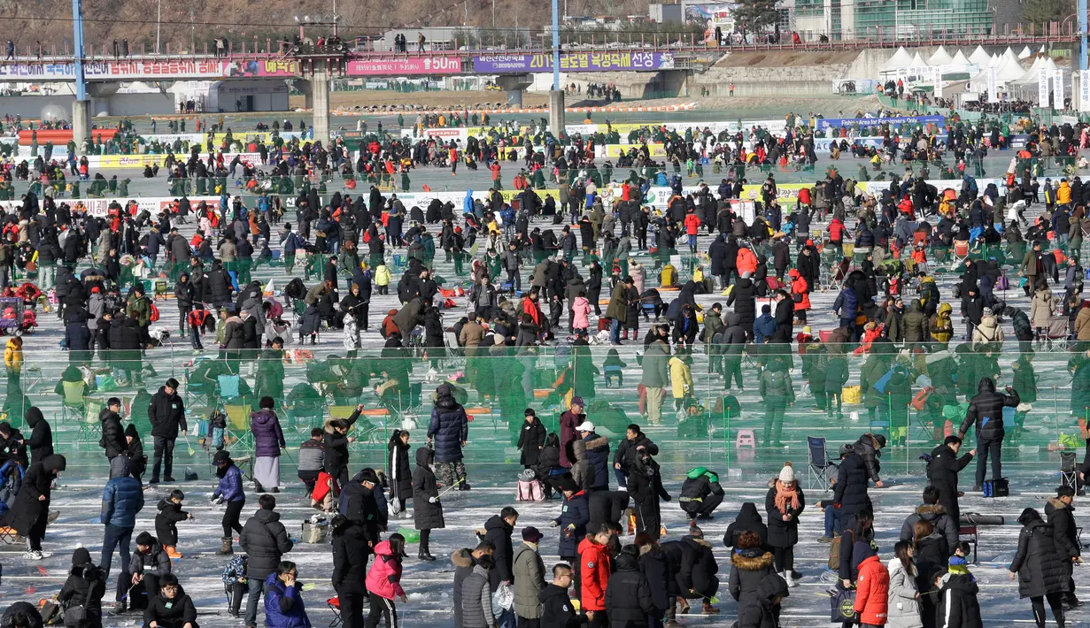 Peserta memancing ikan trout melalui lubang yang mereka buat di atas sungai beku di Hwacheon, Korea Selatan, Sabtu (5/1). Kontes ini merupakan bagian dari festival es tahunan yang menarik lebih dari satu juta pengunjung setiap tahun. (AP/Ahn Young-joon)