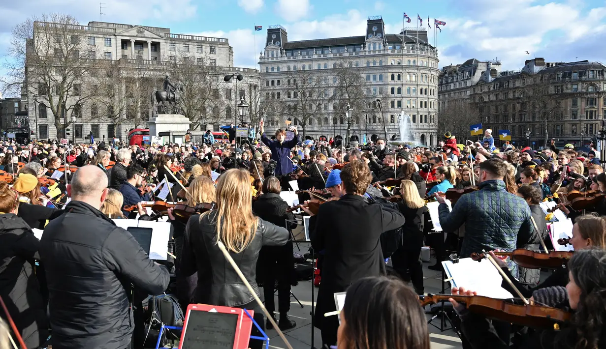 Puluhan musisi ambil bagian dalam pertunjukan flashmob "The Great Gate of Kyiv from pictures at an Exhibition" yang dipimpin seorang komposer Rusia-Inggris terkenal untuk menunjukkan dukungan terhadap Ukraina setelah invasi Rusia, di Trafalgar Square, London, Minggu (6/3/2022). (JUSTIN TALLIS/AFP)