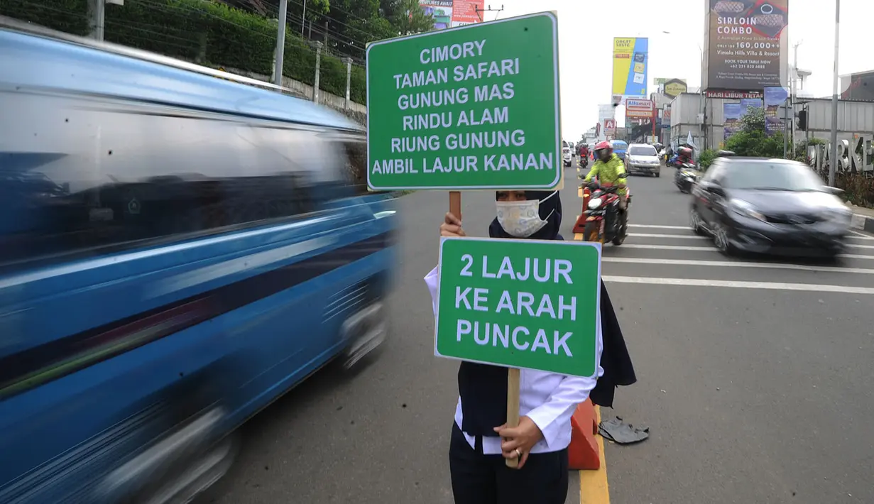 Petugas Badan Pengelola Transportasi Jabodetabek (BPTJ) berdiri sambil membawa papan imbauan saat uji coba sistem kanalisasi 2-1 Jalur Puncak di kawasan Gadog, Bogor, Jawa Barat, Minggu (27/10/2019). (merdeka.com/Arie Basuki)