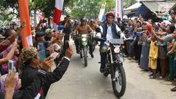 Warga menyambut kedatangan Presiden Joko Widodo saat mengendarai motor trail di Muara Gembong, Bekasi (1/11).  Jokowi mengenakan kemeja putih, celana jeans, dengan balutan jaket rompi berwarna hitam. (Liputan6.com/Biro Pers Kepresidenan/Agus Suparto)